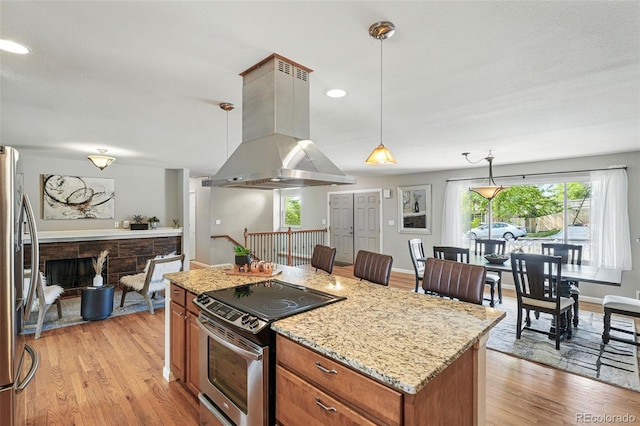 3570 E Arapahoe Pl, Centennial, CO 80122 - kitchen with island exhaust hood, appliances with stainless steel finishes, brown cabinets, light wood finished floors, and recessed lighting