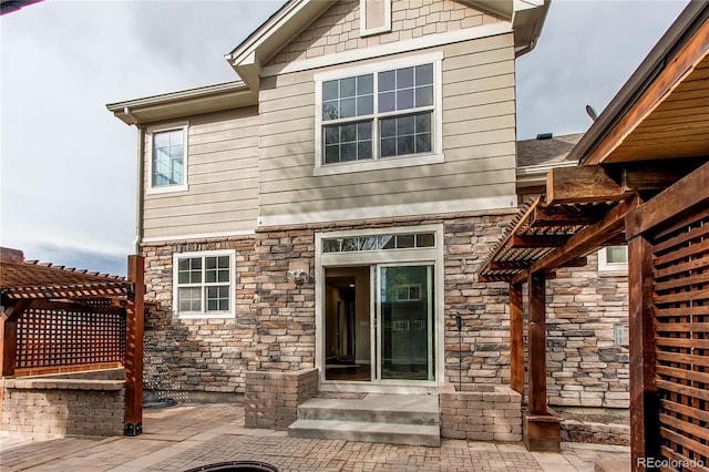 5597 S Buchanan St, Aurora, CO 80016 - rear view of property featuring stone siding, a patio area, and a pergola