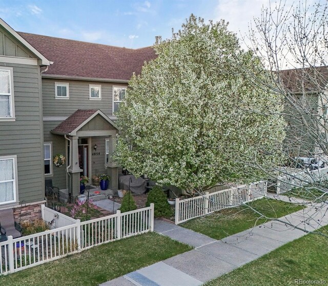 view of front of home featuring board and batten siding, a shingled roof, fence private yard, and a front yard