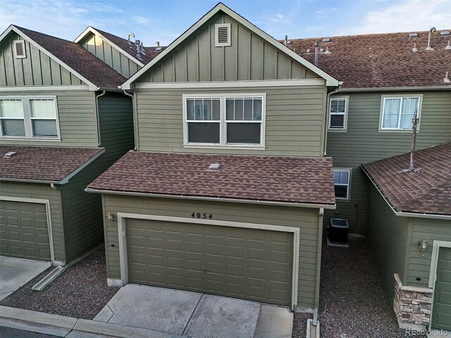 view of property featuring board and batten siding, concrete driveway, a shingled roof, and a garage