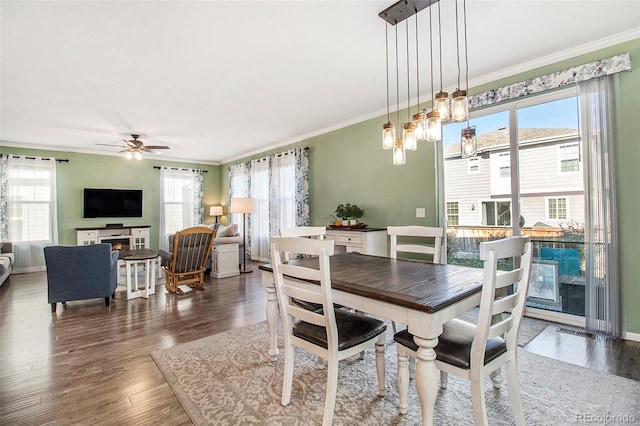 dining room with crown molding, ceiling fan, a healthy amount of sunlight, and dark hardwood / wood-style floors