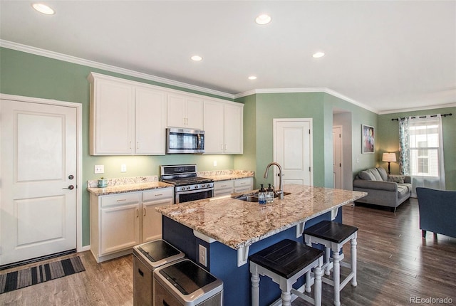 kitchen with a kitchen island with sink, white cabinets, sink, dark hardwood / wood-style flooring, and stainless steel appliances