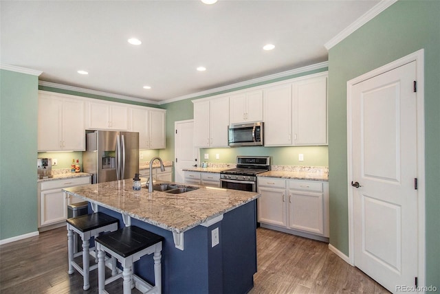 kitchen with stainless steel appliances, white cabinetry, a center island with sink, and sink