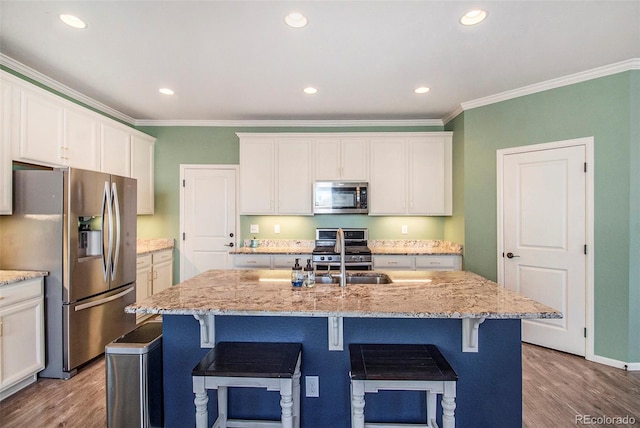 kitchen with light stone counters, sink, an island with sink, and appliances with stainless steel finishes