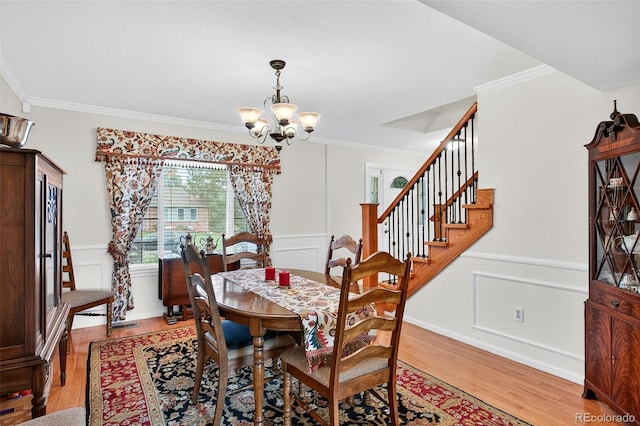 10328 W Crestone Mtn, Littleton, CO 80127 - dining area featuring a chandelier, ornamental molding, light wood-style floors, a decorative wall, and stairway