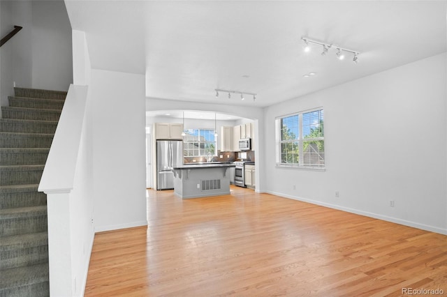 701 N Roslyn St Unit 36, Denver, CO 80230 - unfurnished living room featuring track lighting, light wood-type flooring, stairs, and baseboards