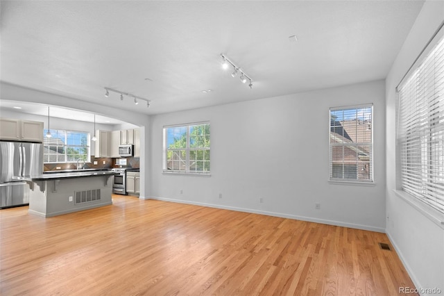 701 N Roslyn St Unit 36, Denver, CO 80230 - unfurnished living room with light wood finished floors, rail lighting, and baseboards