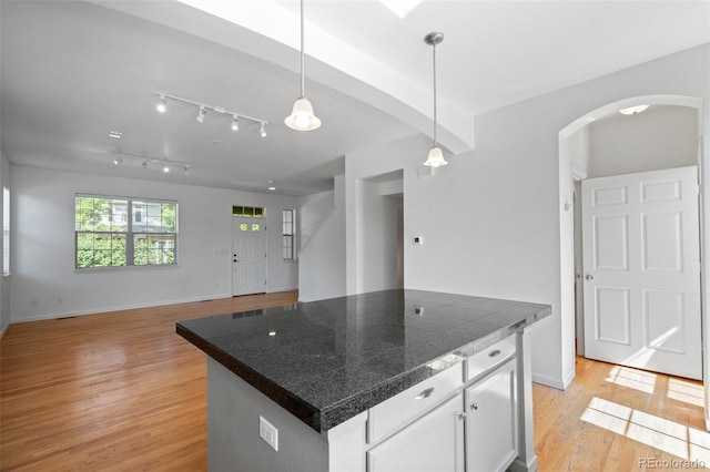 701 N Roslyn St Unit 36, Denver, CO 80230 - kitchen with arched walkways, light wood-style flooring, white cabinetry, pendant lighting, and tile countertops