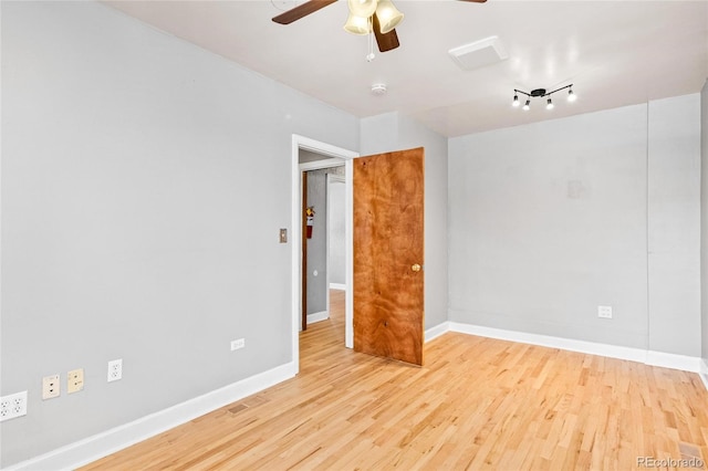 empty room featuring ceiling fan, light wood finished floors, and baseboards