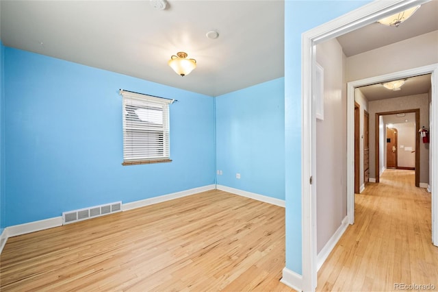 unfurnished room featuring light wood-type flooring, baseboards, and visible vents