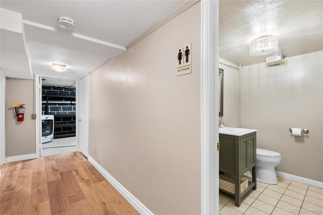 hallway with light tile patterned floors, washer / clothes dryer, and baseboards