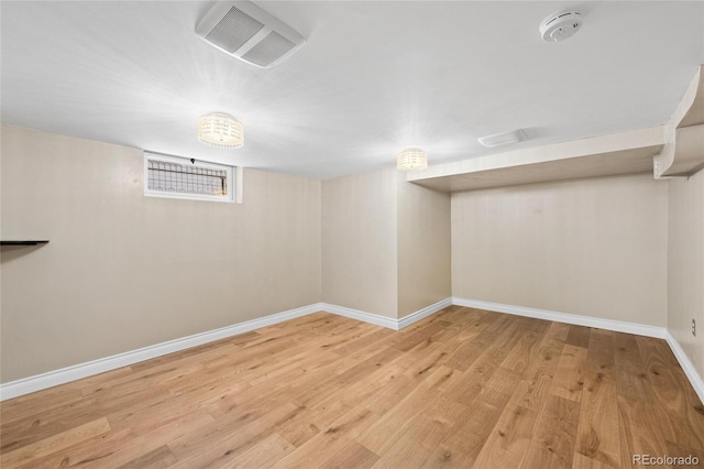 basement with light wood finished floors, visible vents, and baseboards