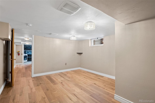 below grade area with visible vents, light wood finished floors, washer / dryer, and baseboards