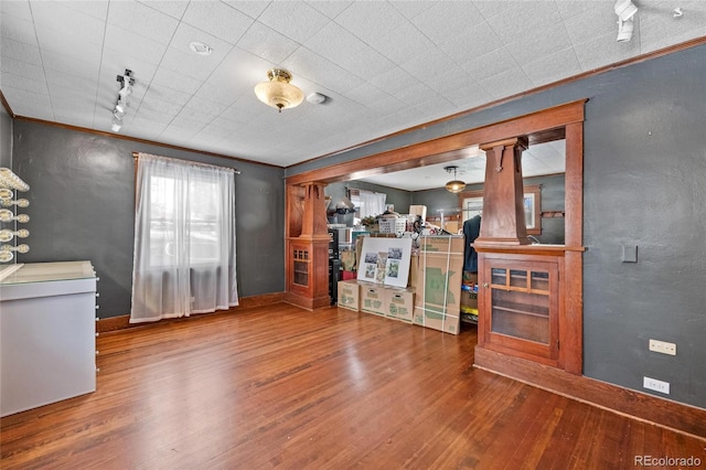 unfurnished living room featuring crown molding and wood finished floors