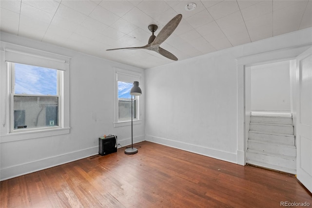 spare room featuring a ceiling fan, baseboards, and wood finished floors