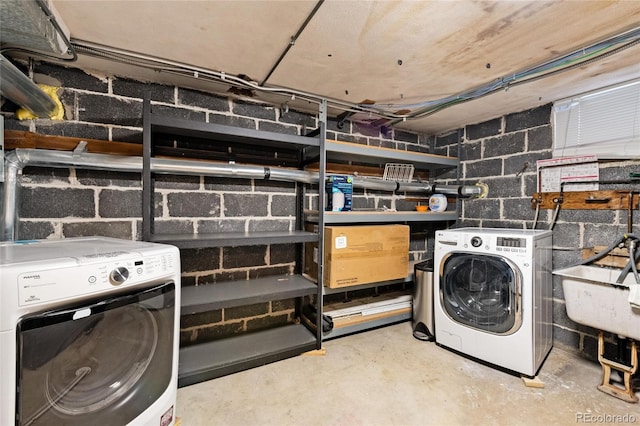 clothes washing area featuring laundry area, separate washer and dryer, a sink, and concrete block wall