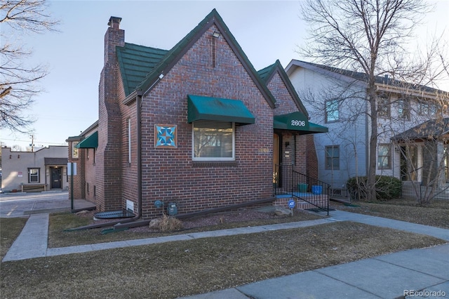 view of front facade with brick siding and a chimney