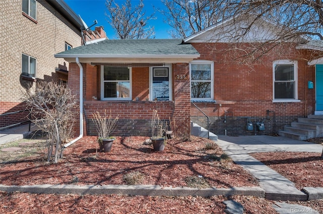 view of front facade featuring brick siding and roof with shingles