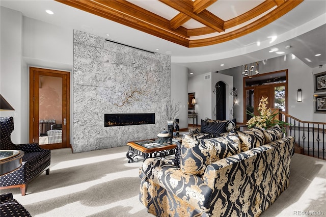 living room featuring a high end fireplace, coffered ceiling, carpet floors, ornamental molding, and beam ceiling