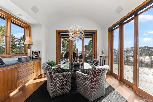 dining space featuring an inviting chandelier, a healthy amount of sunlight, and lofted ceiling