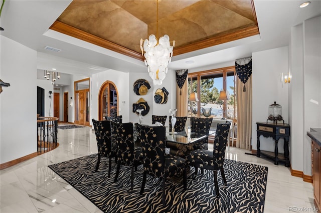 dining space with a tray ceiling, ornamental molding, and a chandelier