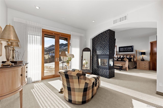 sitting room featuring a tile fireplace, a healthy amount of sunlight, light colored carpet, and french doors