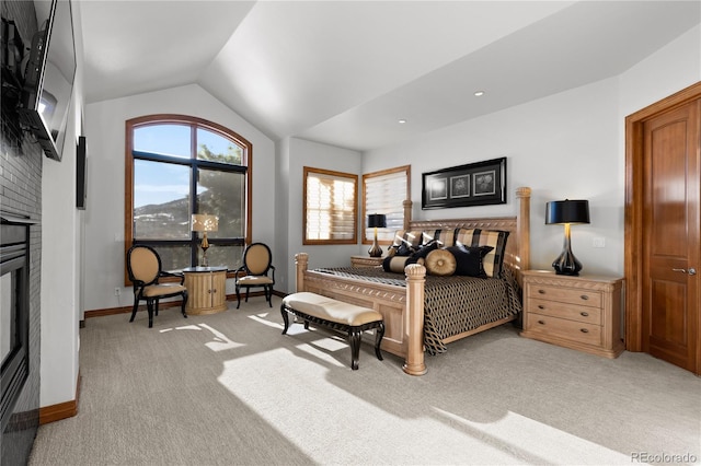 bedroom featuring light carpet, vaulted ceiling, and a brick fireplace