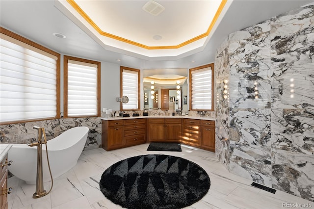 bathroom featuring vanity, a raised ceiling, ornamental molding, and a tub