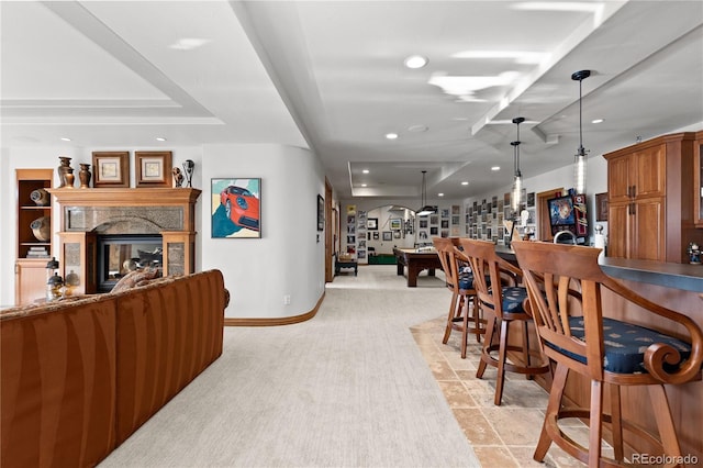 dining area featuring indoor bar, a high end fireplace, and a tray ceiling