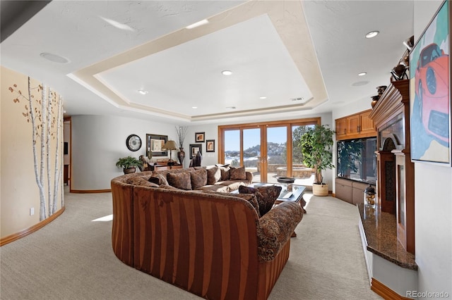 carpeted living room with a tray ceiling and french doors