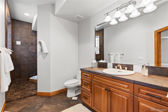 bathroom with vanity, toilet, and a tile shower