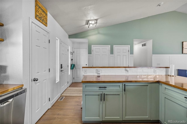 kitchen with dishwasher, vaulted ceiling, green cabinetry, and butcher block countertops