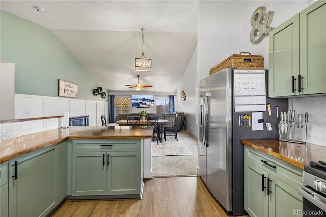 kitchen featuring butcher block counters, stainless steel appliances, green cabinets, and lofted ceiling