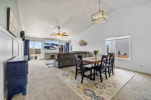 dining space featuring ceiling fan with notable chandelier, baseboards, lofted ceiling, and carpet floors