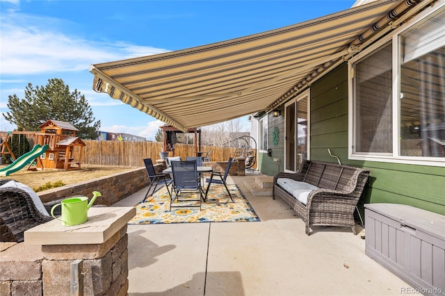 view of patio with outdoor dining space, a playground, and a fenced backyard