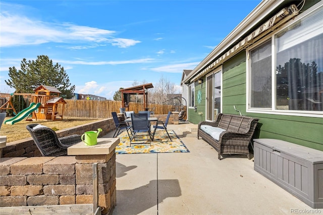 view of patio with outdoor dining area, a fenced backyard, and a playground