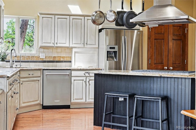 19640 Four Winds Way, Monument, CO 80132 - kitchen featuring appliances with stainless steel finishes, range hood, decorative backsplash, a kitchen bar, and light stone countertops