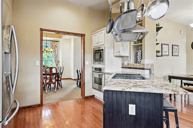 19640 Four Winds Way, Monument, CO 80132 - kitchen with stainless steel appliances, a kitchen bar, a chandelier, light wood finished floors, and a peninsula