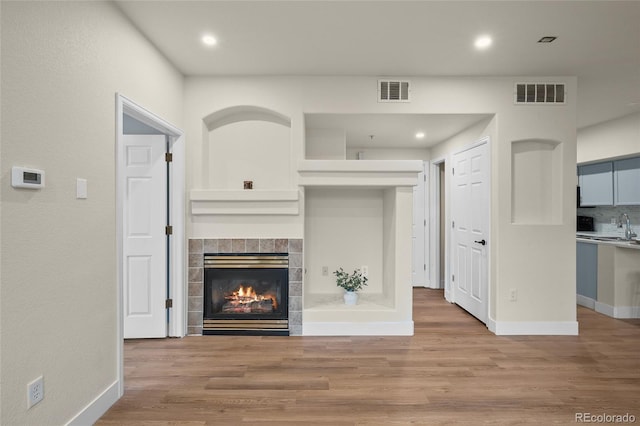 9590 E Florida Ave Unit 1025, Denver, CO 80247 - unfurnished living room featuring a tile fireplace, baseboards, a sink, wood finished floors, and recessed lighting