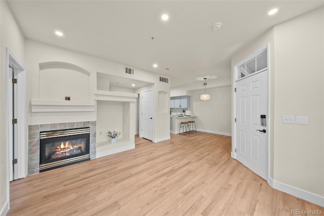 9590 E Florida Ave Unit 1025, Denver, CO 80247 - unfurnished living room featuring light wood-type flooring, a tile fireplace, baseboards, and recessed lighting