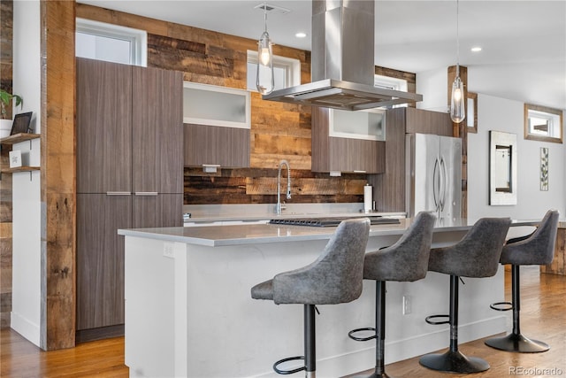 1930 W 35th Ave, Denver, CO 80211 - kitchen featuring modern cabinets, island exhaust hood, light wood-style floors, a center island, and a breakfast bar