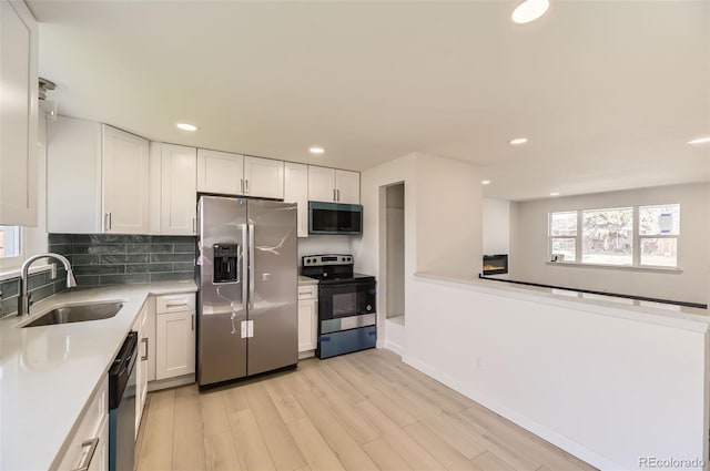 kitchen with light wood-style flooring, a sink, white cabinetry, and stainless steel appliances