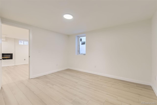 spare room featuring a healthy amount of sunlight, light wood finished floors, and baseboards