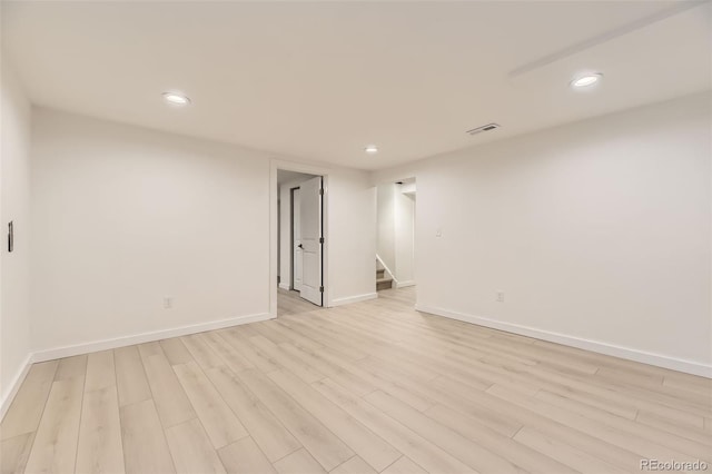 spare room with visible vents, baseboards, light wood finished floors, recessed lighting, and stairs