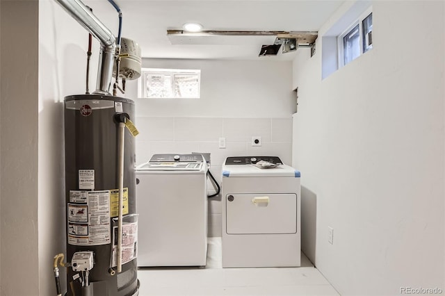 washroom featuring laundry area, a healthy amount of sunlight, gas water heater, and washer and clothes dryer