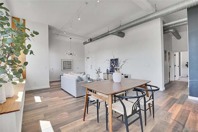 2501 15th St Unit 3F, Denver, CO 80211 - dining area with a towering ceiling, light wood-style flooring, a chandelier, and baseboards