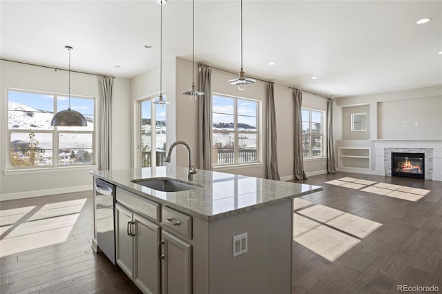 kitchen with a healthy amount of sunlight, light stone countertops, sink, and hanging light fixtures