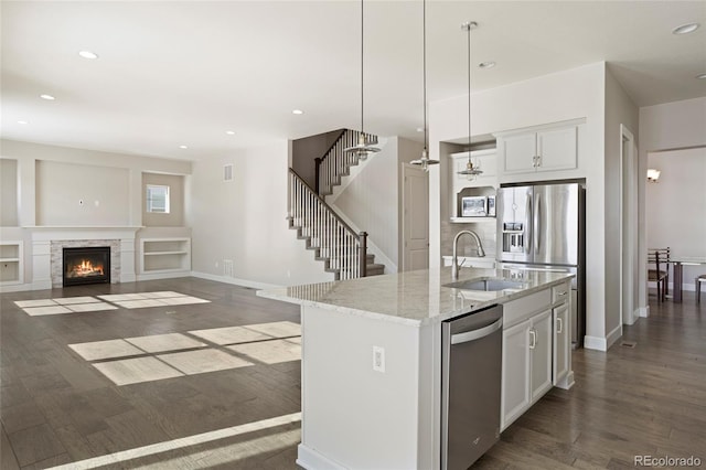 kitchen with white cabinetry, sink, dark hardwood / wood-style flooring, a kitchen island with sink, and appliances with stainless steel finishes