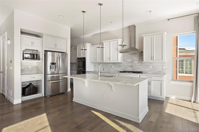 kitchen featuring white cabinets, appliances with stainless steel finishes, decorative light fixtures, and wall chimney exhaust hood