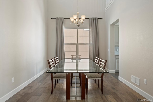 dining space featuring a towering ceiling, an inviting chandelier, and dark wood-type flooring